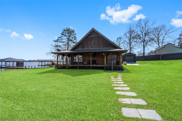 rear view of house with a water view and a lawn