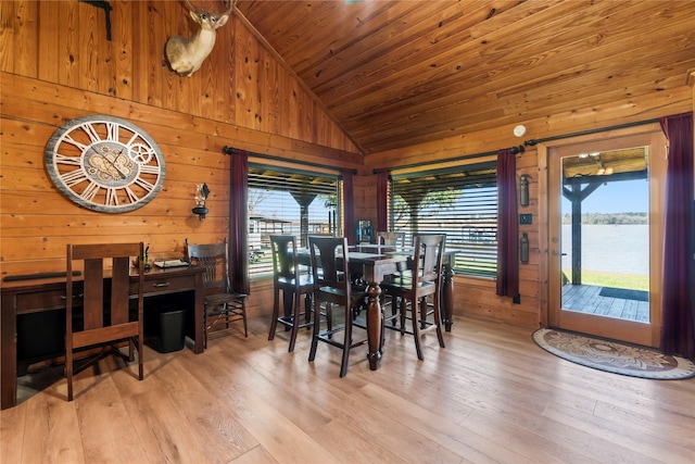 dining space with light wood-type flooring, lofted ceiling, a water view, and plenty of natural light