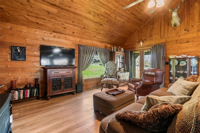 living room featuring vaulted ceiling, light wood-type flooring, ceiling fan, wooden ceiling, and wooden walls