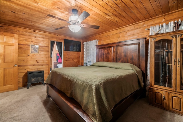 carpeted bedroom with ceiling fan, wood ceiling, a wood stove, and wooden walls