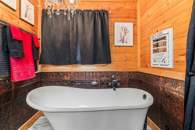 bathroom with a tub to relax in, wood walls, and an inviting chandelier