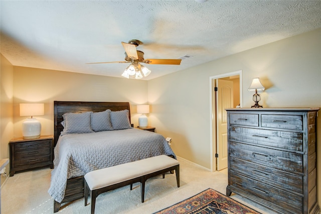 carpeted bedroom featuring ceiling fan and a textured ceiling