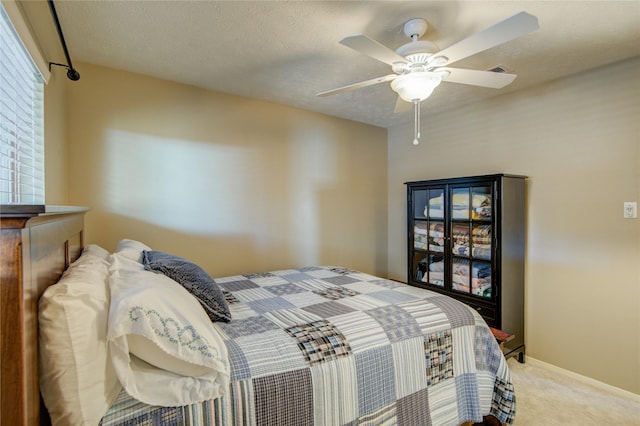 carpeted bedroom featuring ceiling fan and a textured ceiling