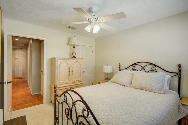 carpeted bedroom with ceiling fan and a textured ceiling