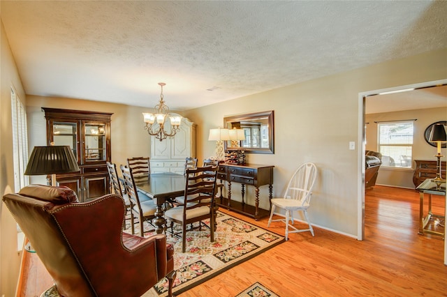 dining room with a textured ceiling, a chandelier, and light hardwood / wood-style flooring