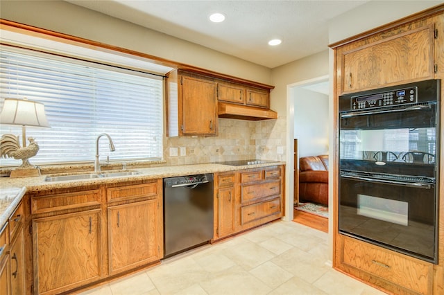 kitchen with backsplash, sink, light stone counters, and black appliances