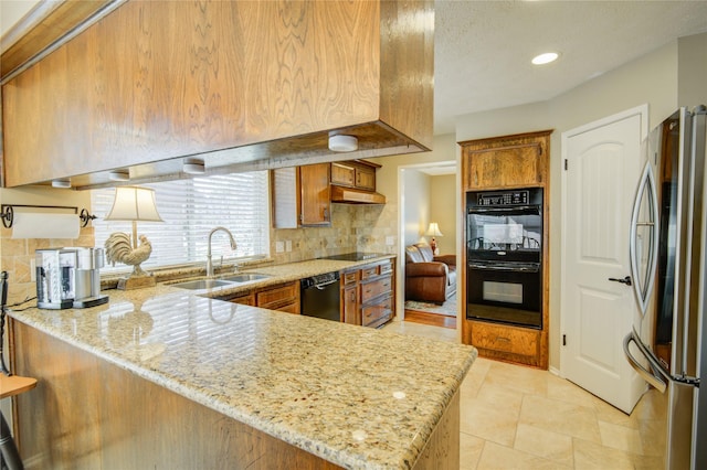 kitchen with black appliances, sink, decorative backsplash, light stone counters, and kitchen peninsula