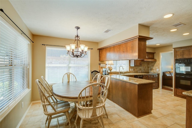 dining space with a chandelier, sink, and a textured ceiling