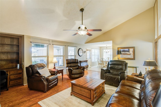 living room featuring hardwood / wood-style flooring, high vaulted ceiling, and ceiling fan with notable chandelier