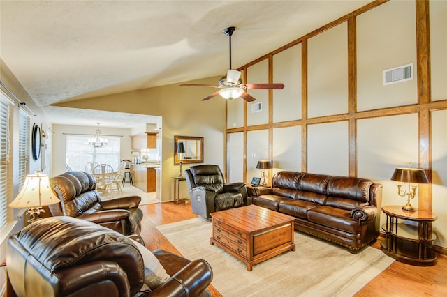 living room with lofted ceiling, ceiling fan with notable chandelier, and light hardwood / wood-style flooring