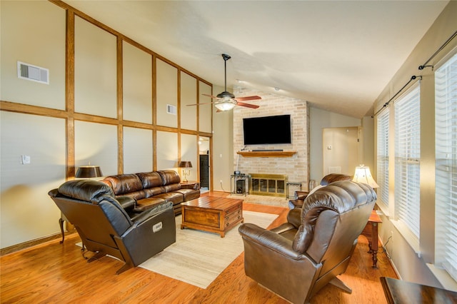 living room featuring a fireplace, high vaulted ceiling, ceiling fan, and light wood-type flooring