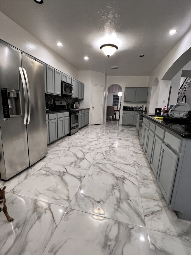 kitchen with decorative backsplash, gray cabinets, a textured ceiling, and appliances with stainless steel finishes