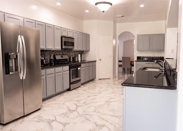 10722 Trail Ridge Dr, Houston, TX 77064 - kitchen featuring appliances with stainless steel finishes, a sink, arched walkways, gray cabinets, and recessed lighting