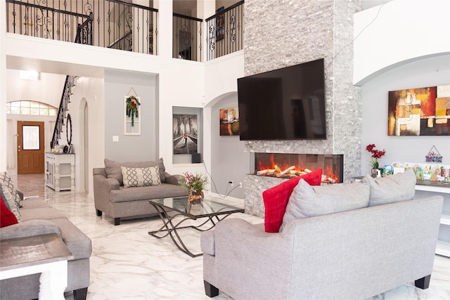 10722 Trail Ridge Dr, Houston, TX 77064 - living room featuring arched walkways, marble tiled floors, a fireplace, and a towering ceiling