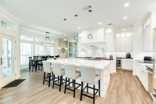 kitchen with a kitchen island, pendant lighting, white cabinets, and beverage cooler