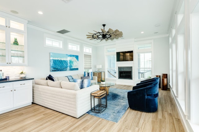 living room with ornamental molding, ceiling fan, and light wood-type flooring