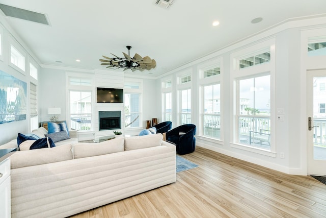 living room featuring ceiling fan, a healthy amount of sunlight, ornamental molding, and light hardwood / wood-style flooring