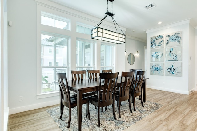 dining area featuring a wealth of natural light, ornamental molding, and light wood-type flooring