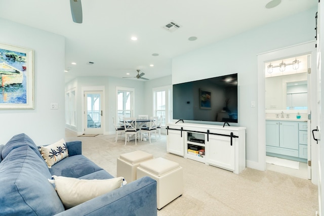 living room featuring ceiling fan, sink, and light carpet