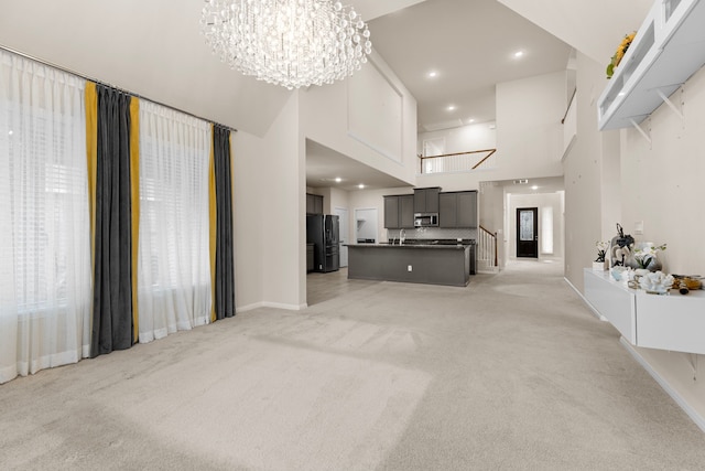 living room with a high ceiling, light colored carpet, and a notable chandelier