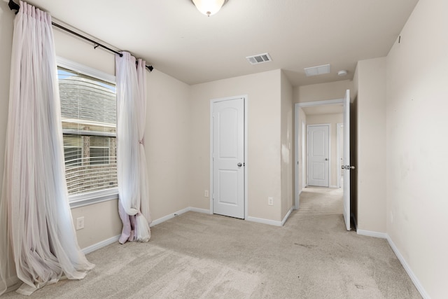 unfurnished bedroom featuring light colored carpet and multiple windows