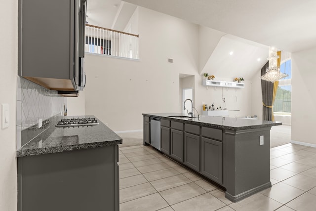 kitchen featuring sink, a center island with sink, dark stone countertops, appliances with stainless steel finishes, and gray cabinets