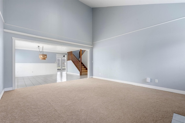 carpeted empty room featuring ornamental molding and a high ceiling