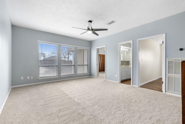 unfurnished bedroom with connected bathroom, carpet floors, a textured ceiling, and ceiling fan