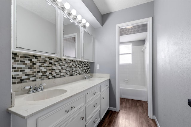 bathroom with vanity, backsplash, hardwood / wood-style floors, and shower / bathing tub combination