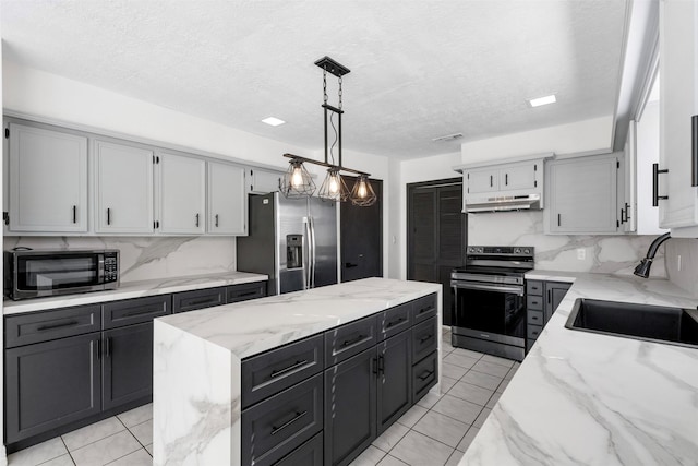 kitchen featuring stainless steel appliances, a kitchen island, hanging light fixtures, and light tile patterned floors