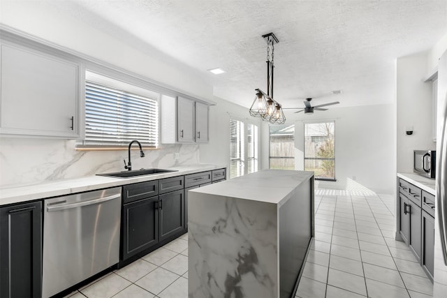 kitchen featuring sink, tasteful backsplash, decorative light fixtures, appliances with stainless steel finishes, and a kitchen island