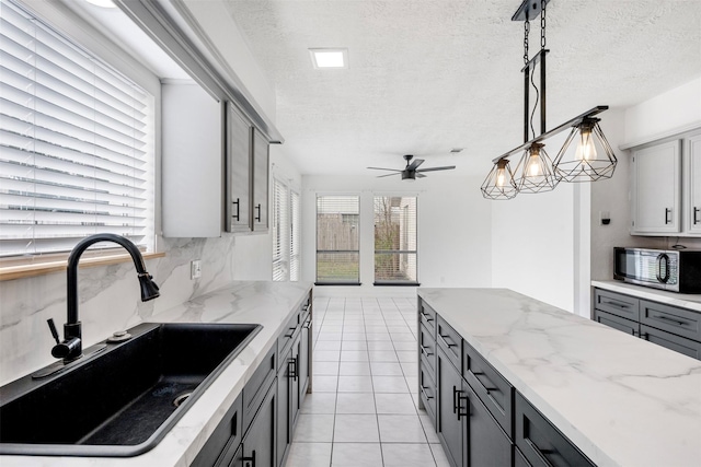 kitchen featuring decorative light fixtures, tasteful backsplash, sink, gray cabinetry, and light tile patterned floors