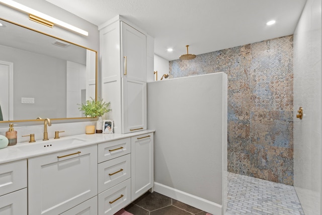 bathroom with vanity, a tile shower, and tile patterned floors