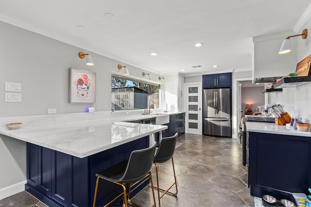 kitchen with crown molding, a breakfast bar area, blue cabinetry, appliances with stainless steel finishes, and kitchen peninsula