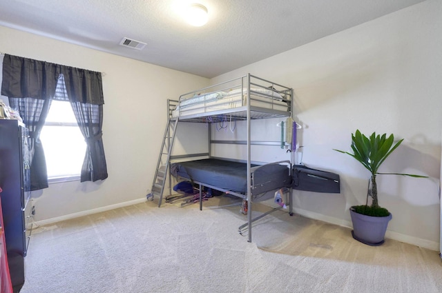 carpeted bedroom with baseboards, visible vents, and a textured ceiling