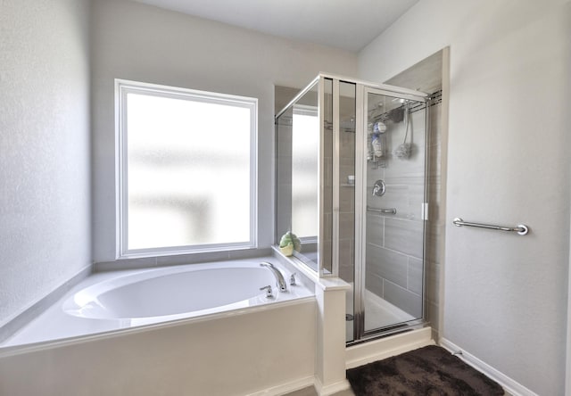 bathroom featuring a stall shower, baseboards, and a bath