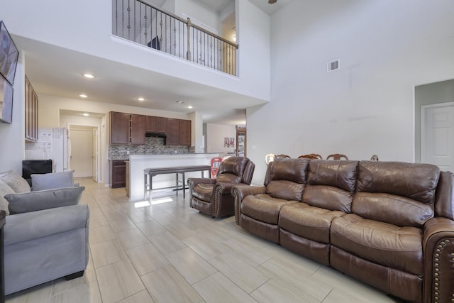 living area with recessed lighting, visible vents, and a high ceiling