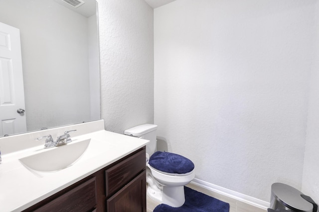 bathroom featuring a textured wall, toilet, visible vents, vanity, and baseboards