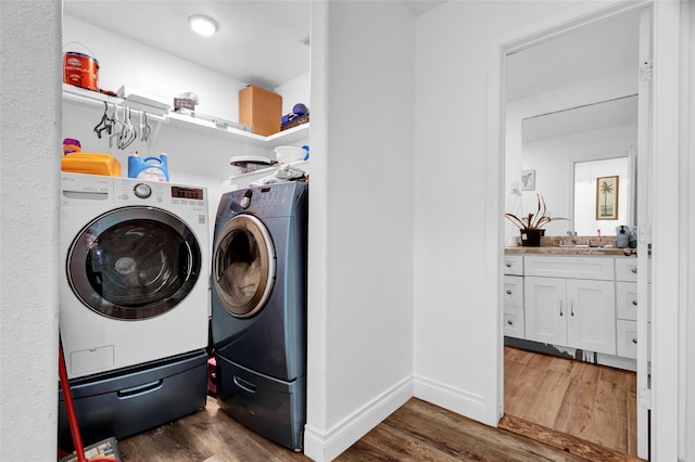 laundry area featuring washing machine and dryer, sink, and dark hardwood / wood-style flooring