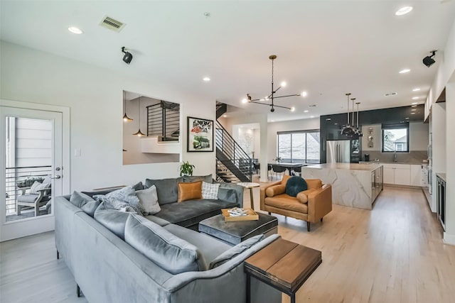 living room with a notable chandelier and light wood-type flooring