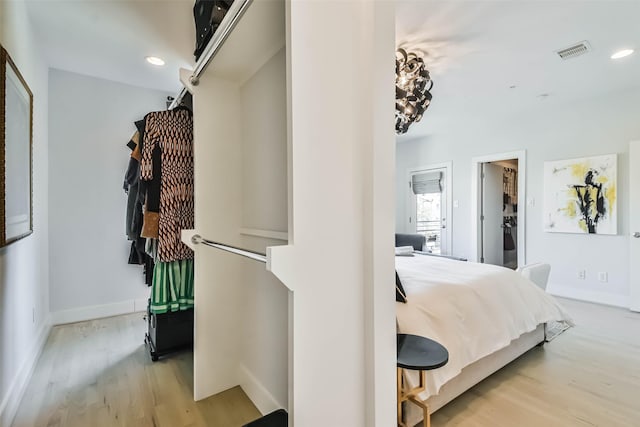 bedroom with a walk in closet and light hardwood / wood-style flooring