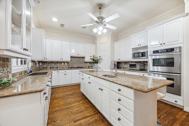 kitchen with white cabinetry, appliances with stainless steel finishes, sink, and a kitchen island with sink