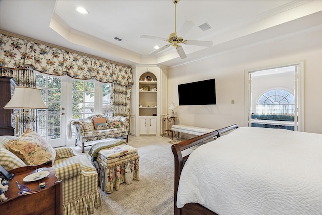 bedroom with multiple windows, a tray ceiling, light carpet, and access to outside