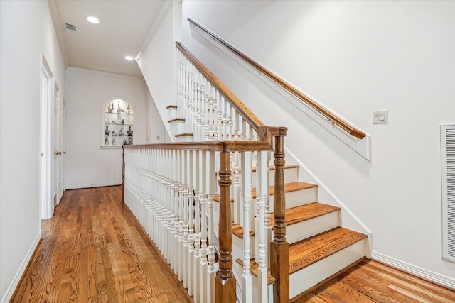 staircase with crown molding and hardwood / wood-style floors