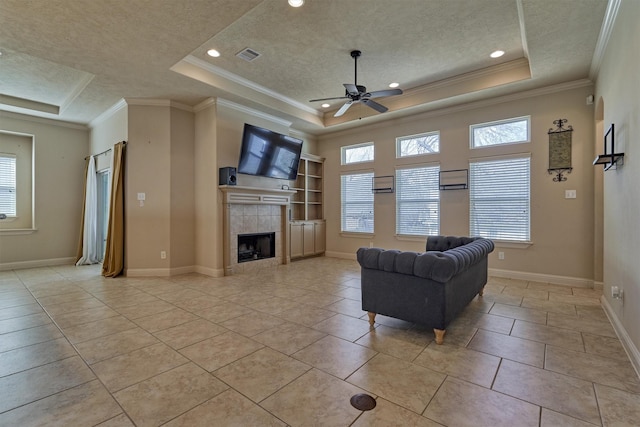 tiled living room featuring ceiling fan, a fireplace, a raised ceiling, and a textured ceiling