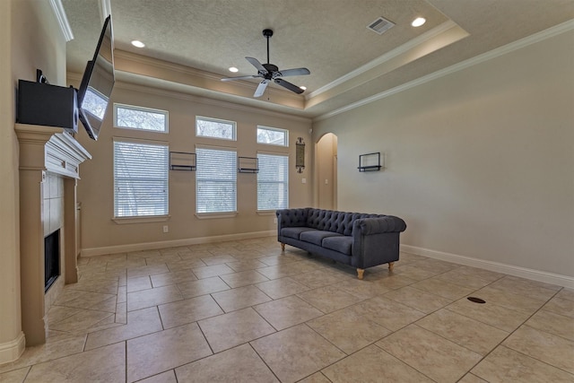 tiled living room featuring crown molding, a textured ceiling, a raised ceiling, and ceiling fan