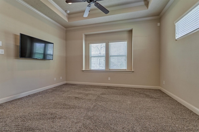 carpeted spare room featuring a raised ceiling, crown molding, plenty of natural light, and ceiling fan