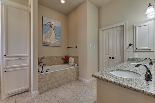 bathroom featuring tile patterned floors, vanity, and tiled bath