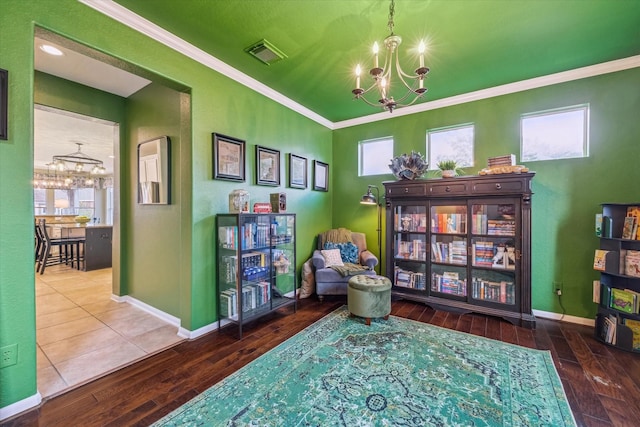 sitting room with a notable chandelier, crown molding, wood-type flooring, and a healthy amount of sunlight