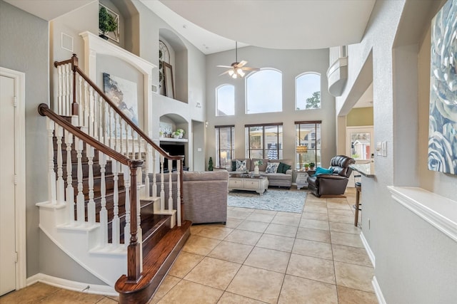 living room with light tile patterned flooring, ceiling fan, and a towering ceiling